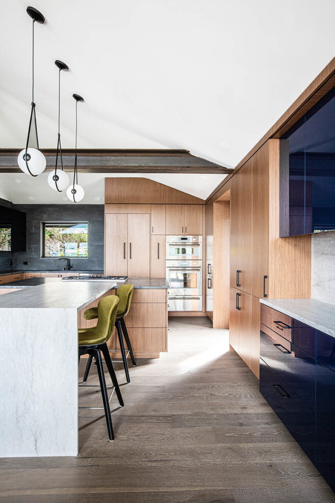 Architectural design kitchen in Seattle, wide plank floors, Sessego pendant lights, stone waterfall island and steel beam.