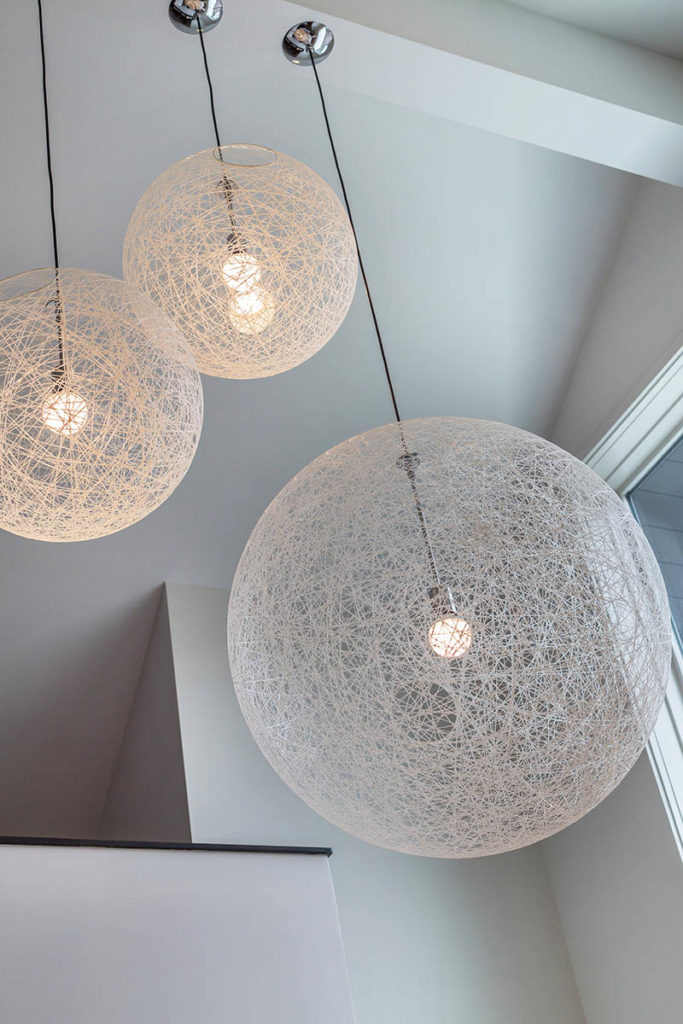 Three pendant lights from Moooi hanging in the two-story entry in Normandy Park from a white vaulted ceiling.