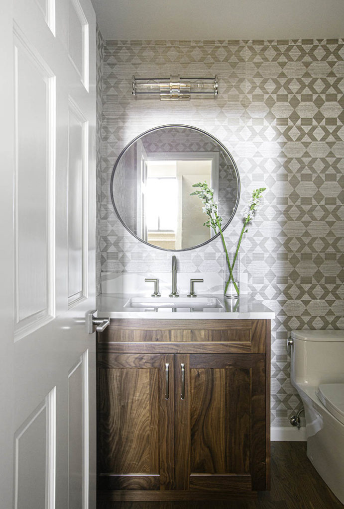 Redesigned powder room in Bellevue with walnut vanity, quartz top, round mirror, Phillip Jeffries wallpaper and Brizo faucet