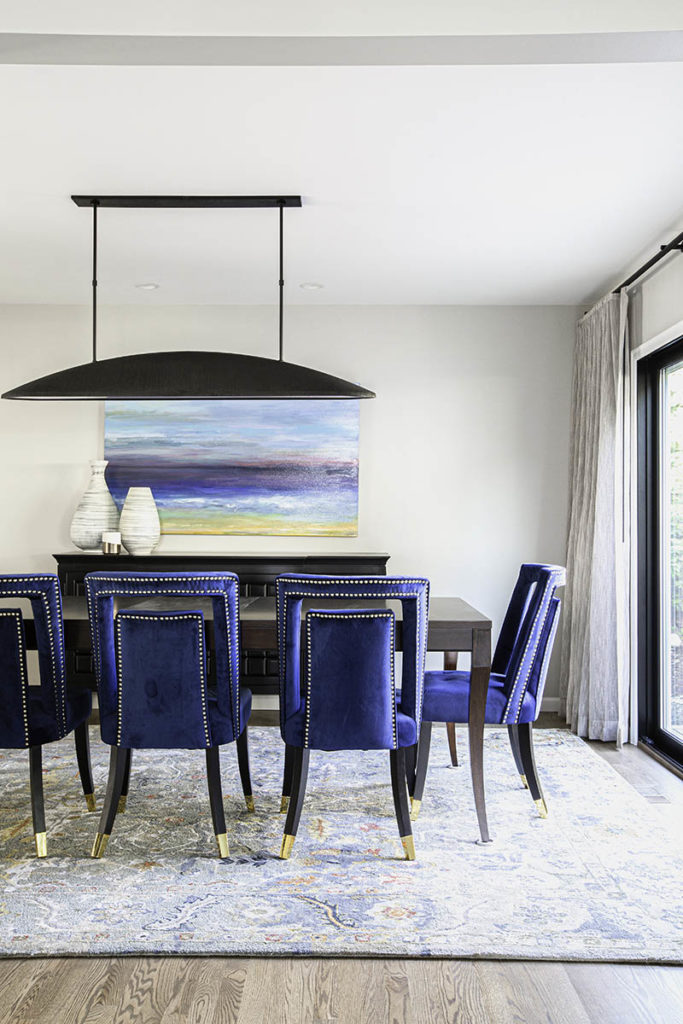 interior designed dining room in Bellevue with studded blue chairs on colorful wool rug, Kelly Wearstler light, custom art