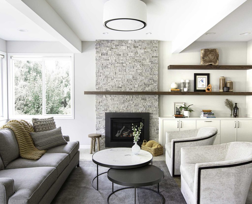 Architectural design living room in Bellevue with stone fireplace, floating walnut shelves, cozy sofa and swivel chairs.