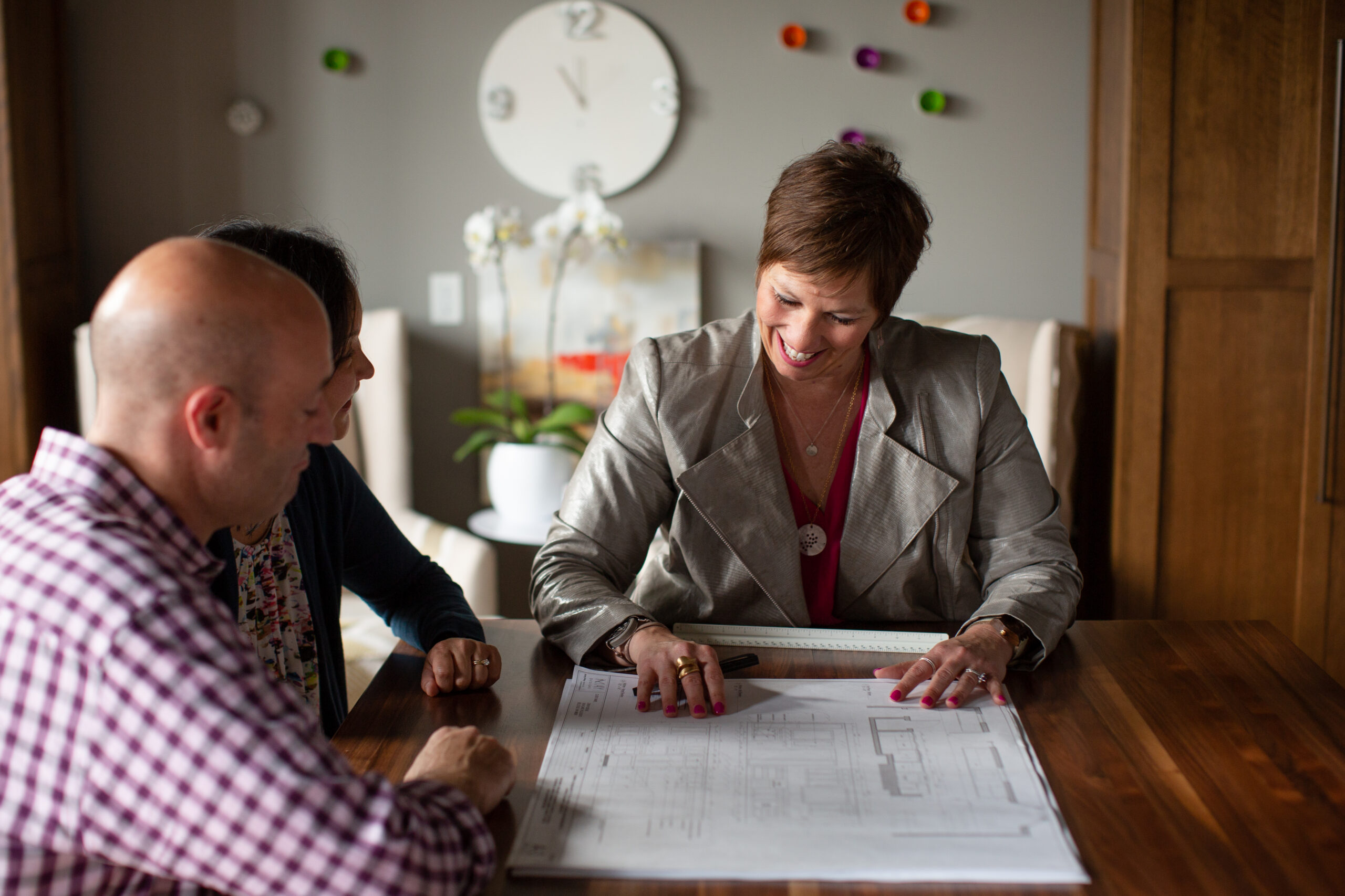 Interior designer Amy May smiling while discussing blueprints with a couple