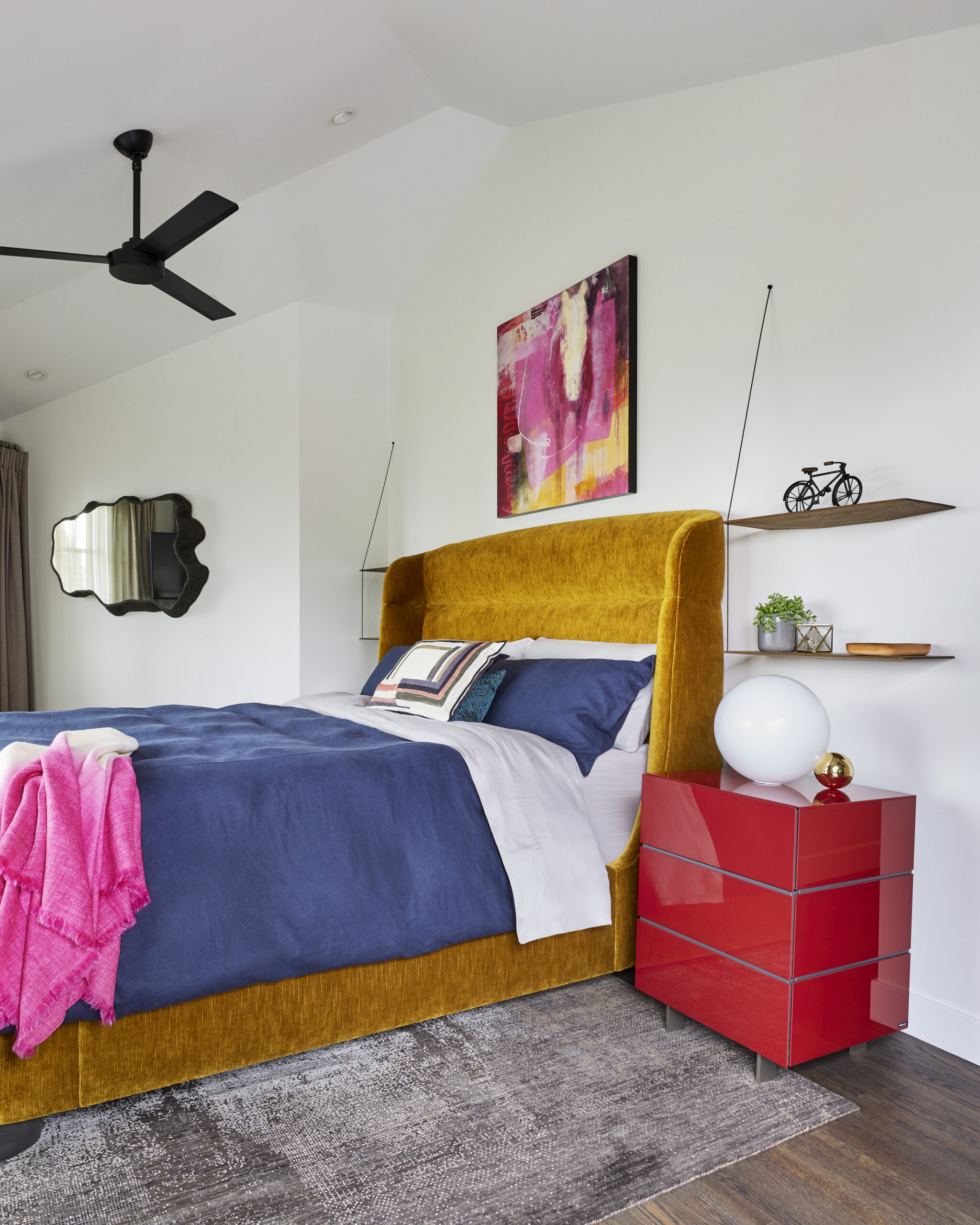 Bold Bedroom with mustard velvet headboard, red glossy nightstand, and pink abstract painting